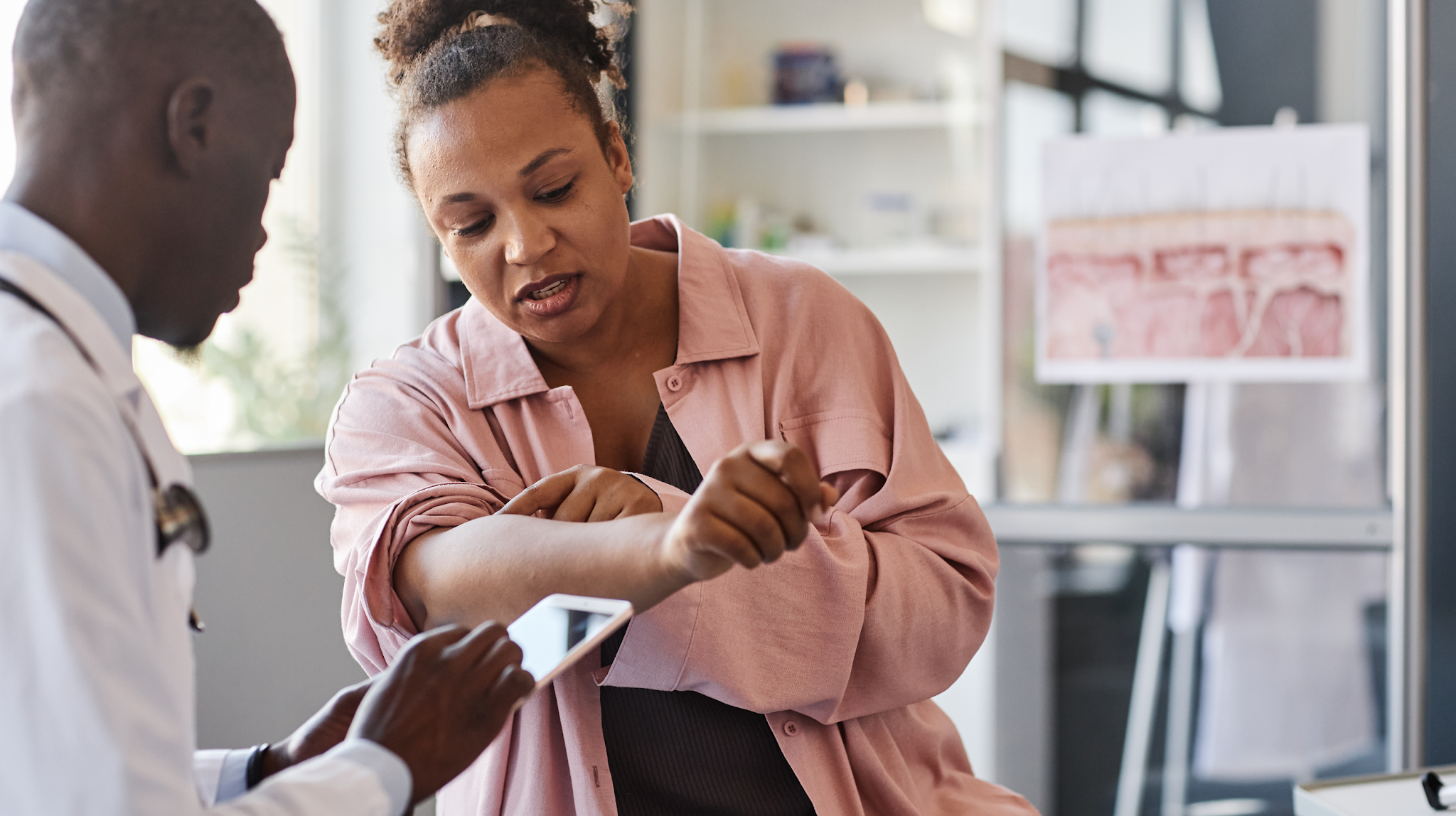 Doctor consulting with a patient who is showing their arm in a medical office